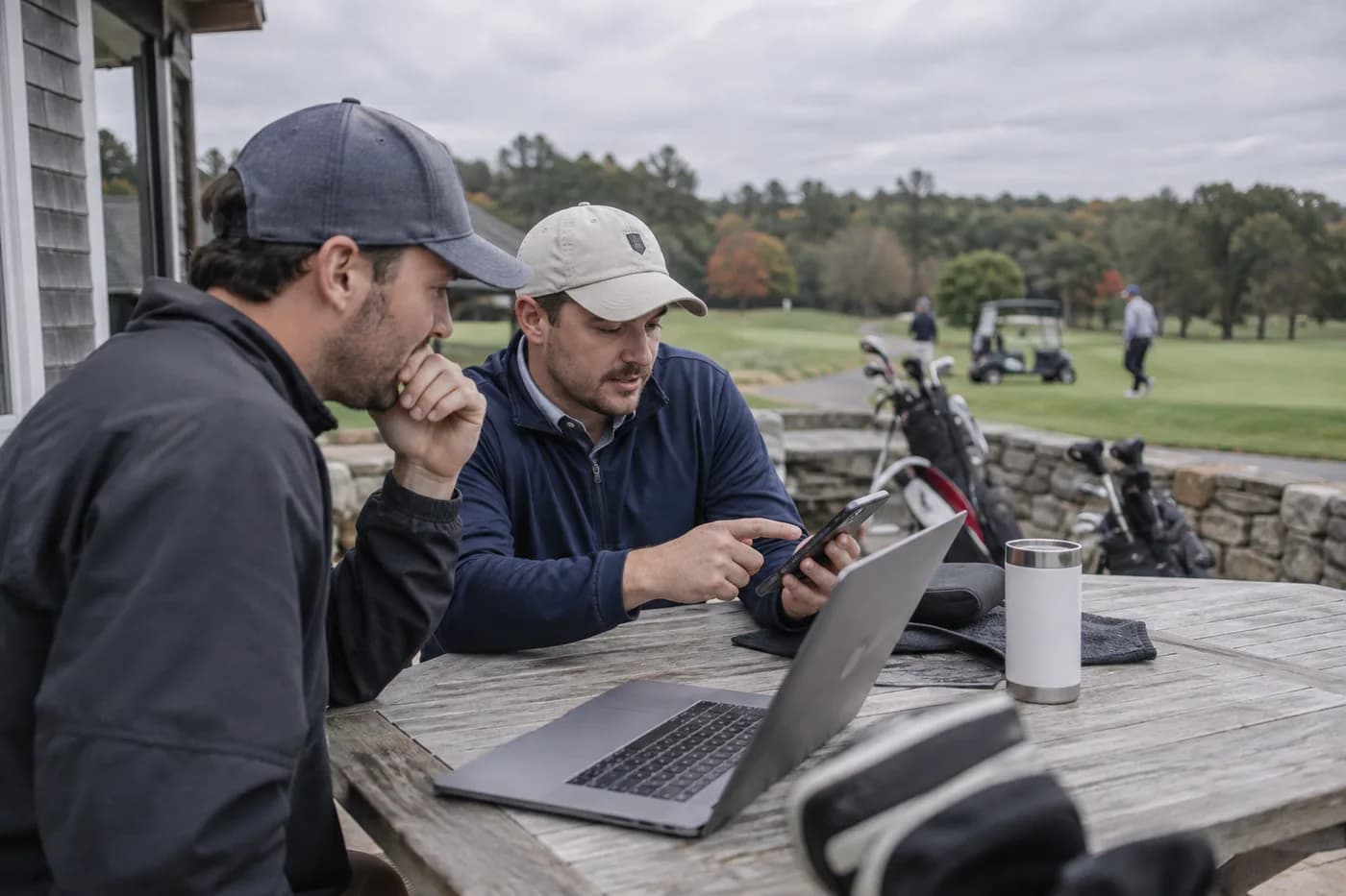 two friends comparing booking options on a laptop and phone