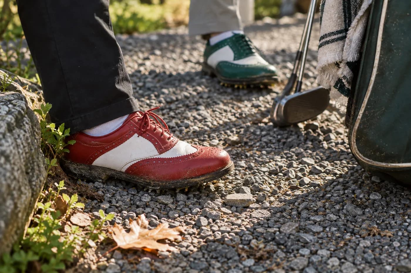 two golfers’ shoes, one red and one green, on a gravel path