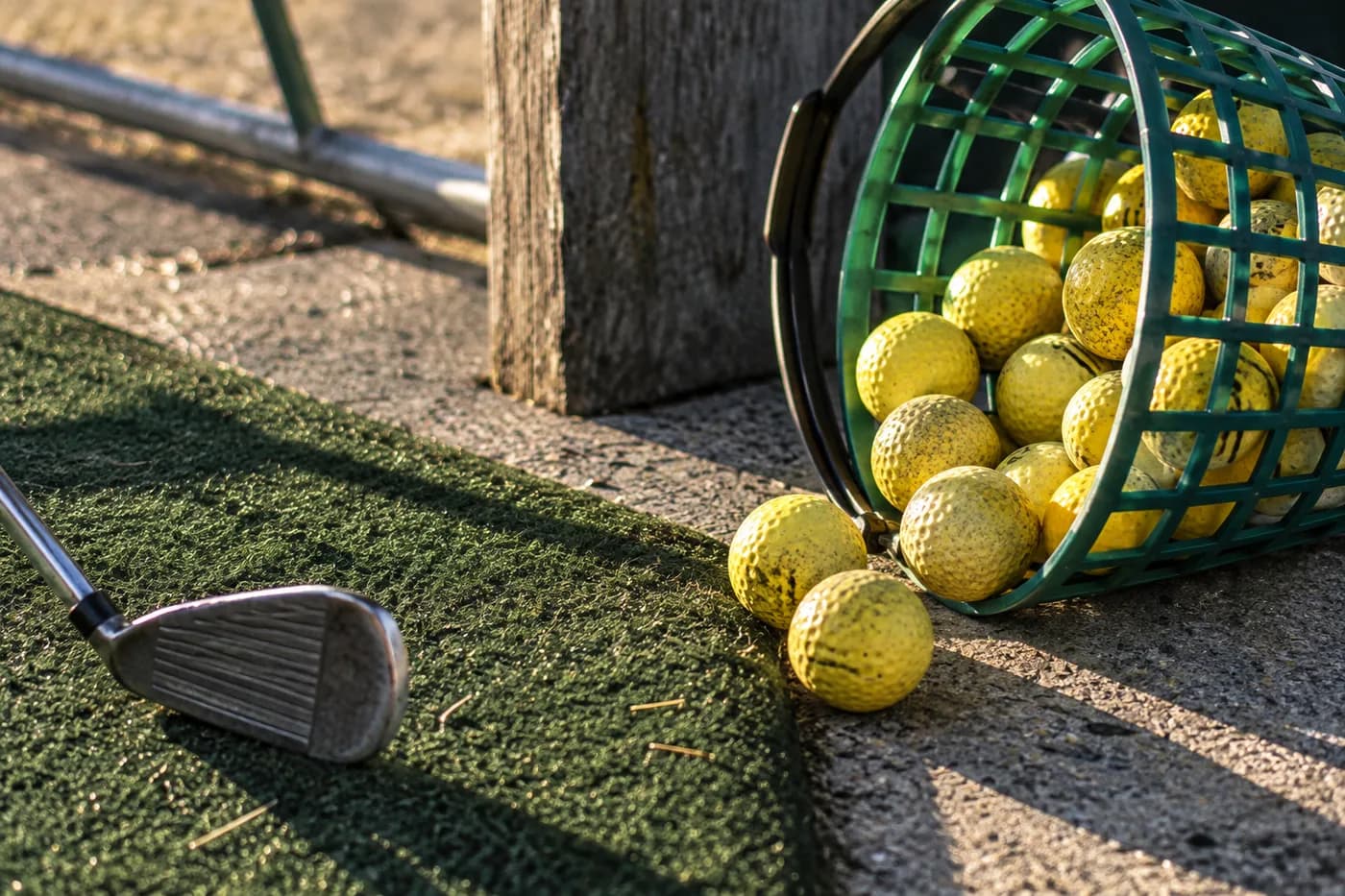 a practice basket with yellow golf balls, low side lighting