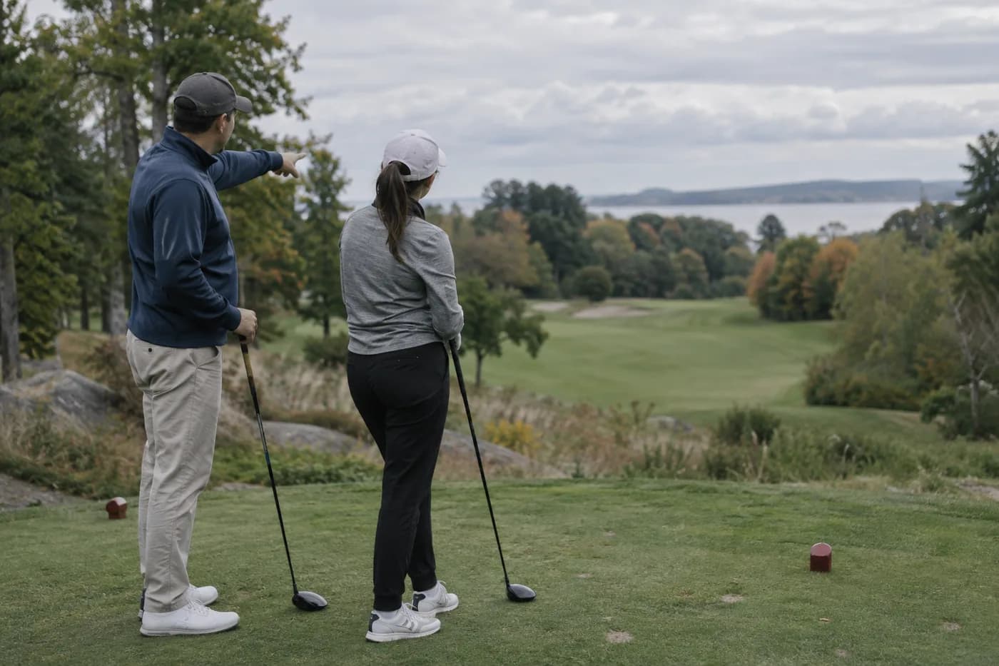 two adult beginners picking a forward tee while one points out the fairway
