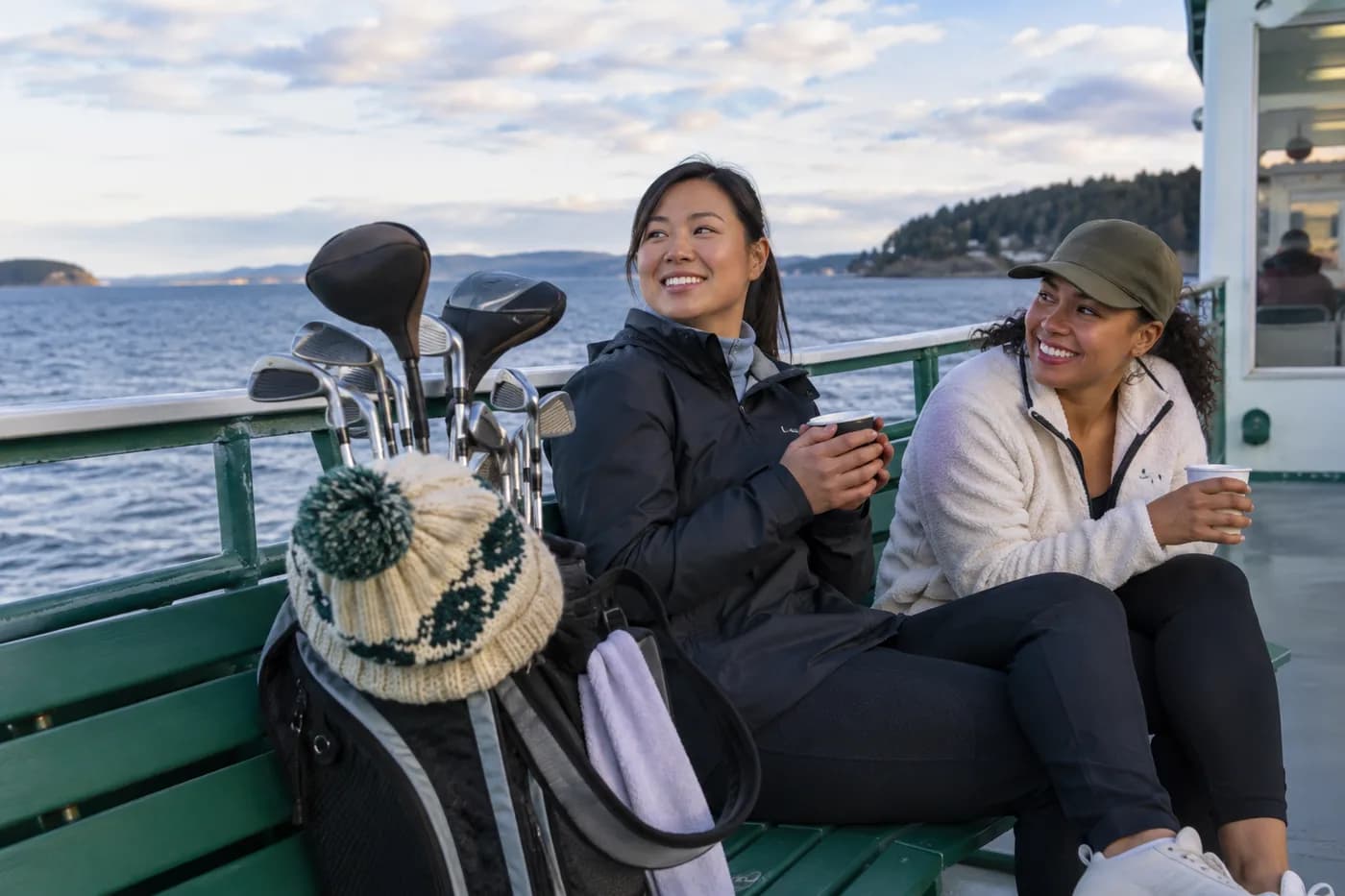 golf clubs and a knitted cap on a ferry-side coastal bench