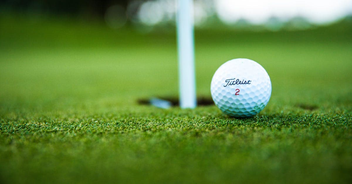 Titleist golf ball resting near the hole on a putting green